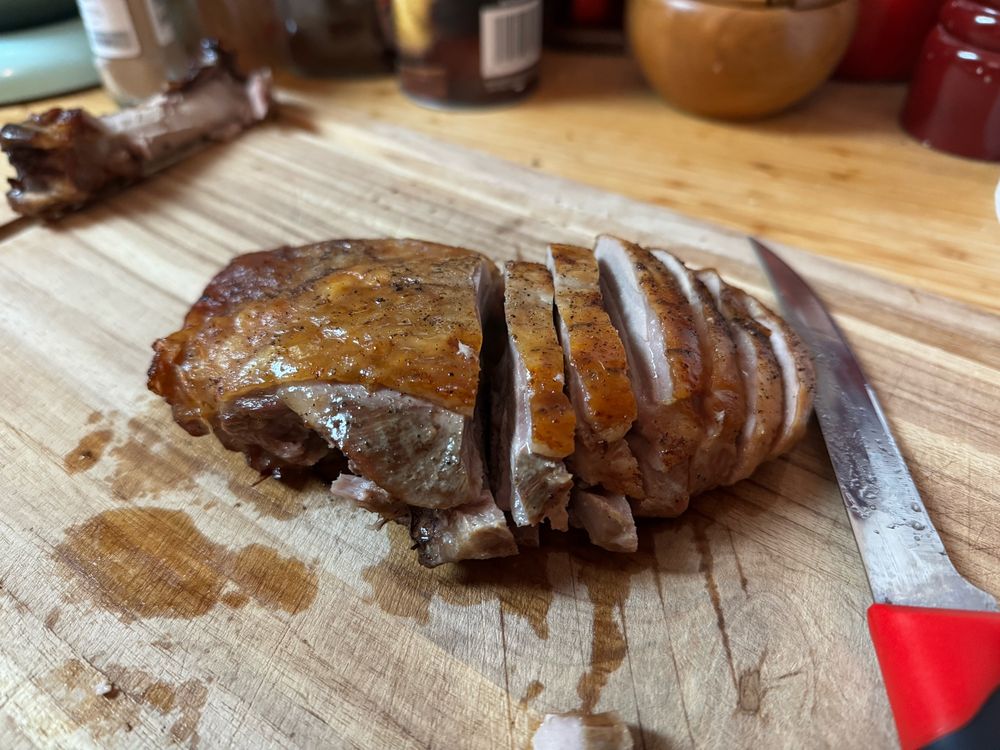The turkey thigh, with glistening browned skin and juicy meat sliced on the cutting board