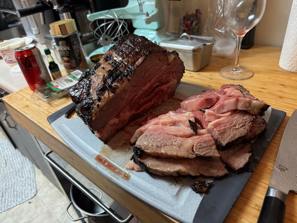 A cross section cut of the prime rib displaying a layer of fat that rendered into the meat. The prime rib is cooked to medium rare/ rare 