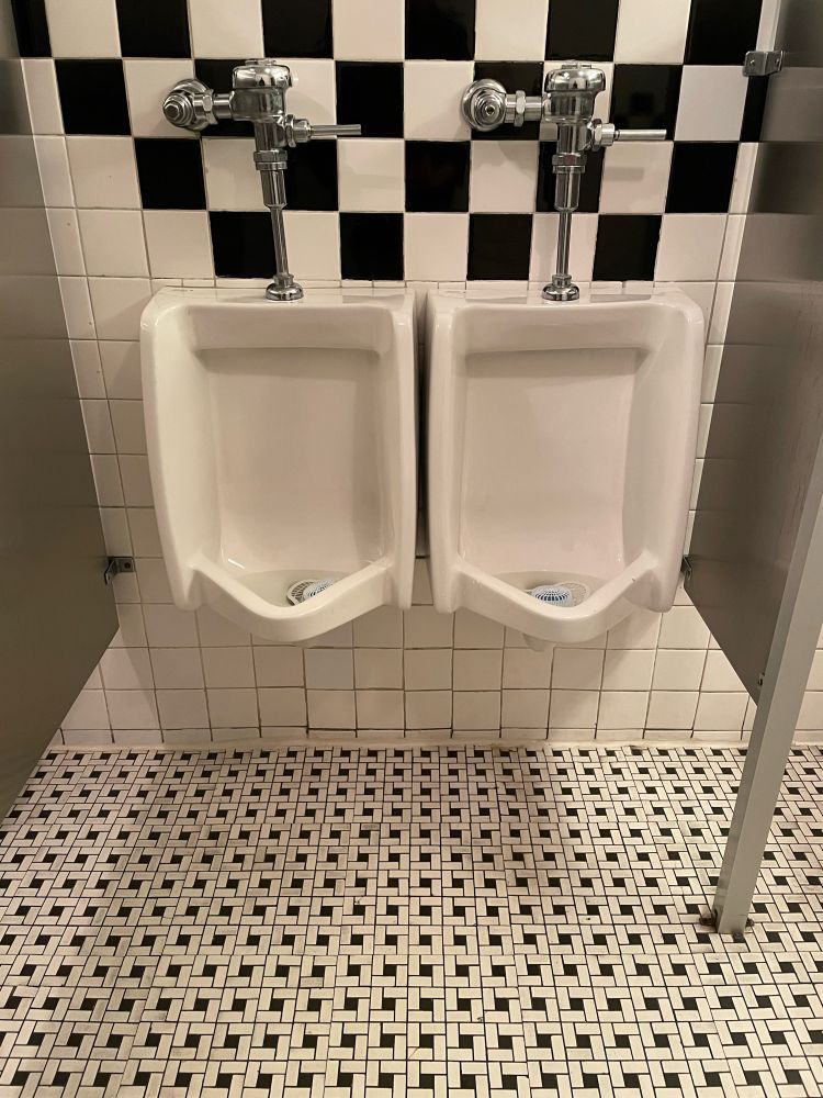Two urinals IMMEDIATELY side by side with no divider or anything, literally like one inch apart from each other