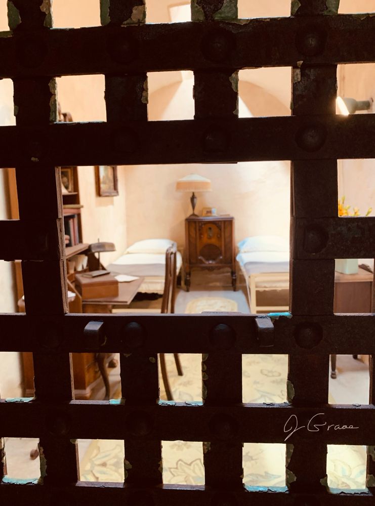 A photo of what is believed to be Al Capone’s cell at Eastern State Penitentiary. There are two single beds, a side table and a writing desk, among other furnishings. 