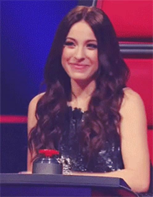 a woman with long hair is smiling while sitting in a chair