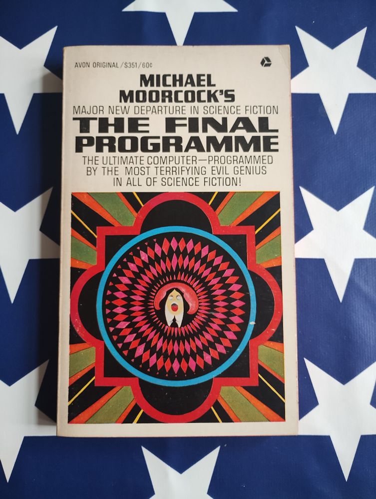 Front cover of the US 1st edition of The Final Programme by Michael Moorcock, Avon, 1968. Illustrated in marvellous Pop-Op style by Harry Douthwaite. A screaming Jerry Cornelius is encircled by pink and black diamonds within another circle of mid-blue. Surrounding this is a background of 4 black  crescents and four triangles, bordered in red. Radiating from this are beams of sage green, orange, black and yellow. The title reads: Michael Moorcock's major new departure in science fiction The Final Programme the ultimate computer - programmed by the most terrifying evil genius in all of science fiction!