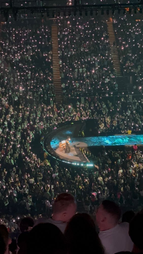 Photo of the Lady Gaga concert at the o2 Arena taken from the right. Gaga is at the end of the runway sitting at and playing a piano. This was part of a small set of acoustic ballads.