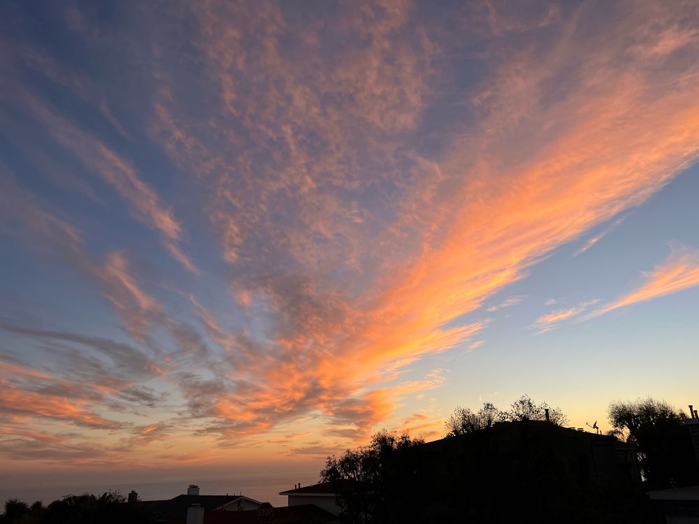 a cloudy sunset but plenty of blue sky visible, clouds tinged with red and gold