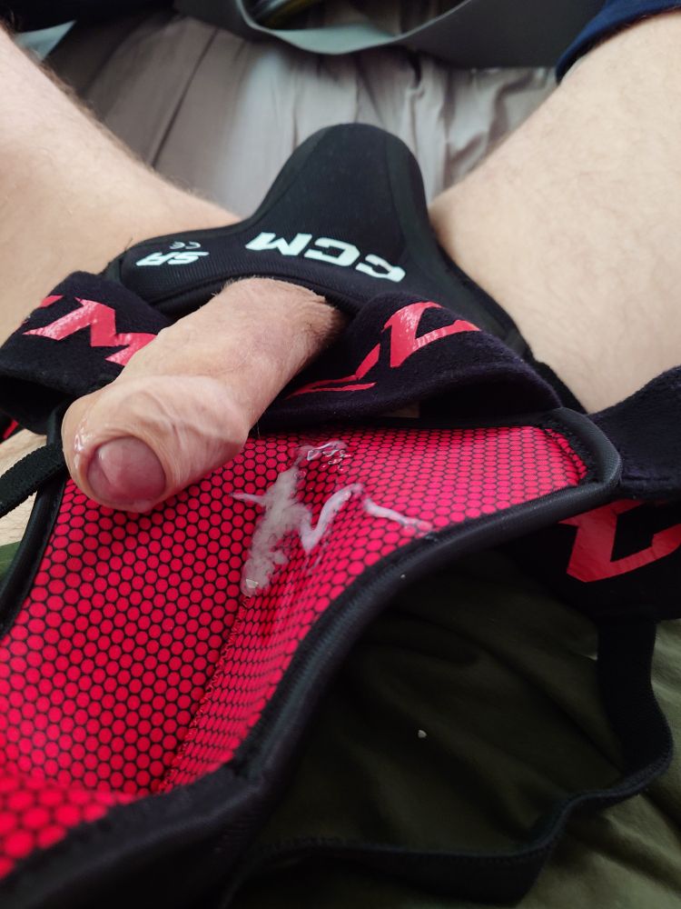 Close-up of me wearing a CCM PRO jock cup, with my cock sticking out and resting on another cup of the same model, but with cum in it