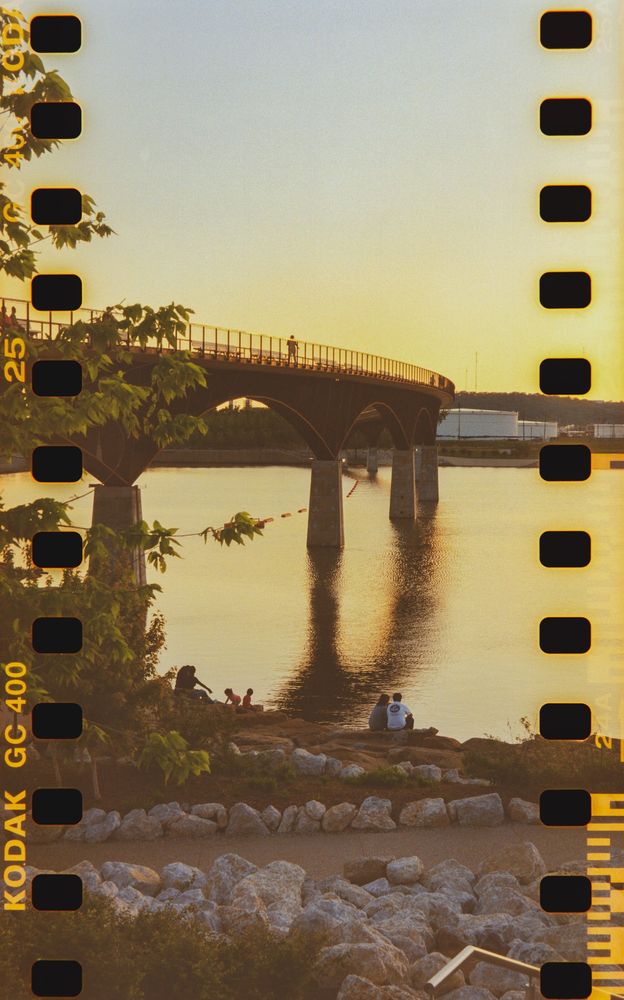 A photograph of a pedestrian bridge during a sunset, shot with the 35mm film strip completely exposed, sprockets and all, by being shot through a medium format camera.