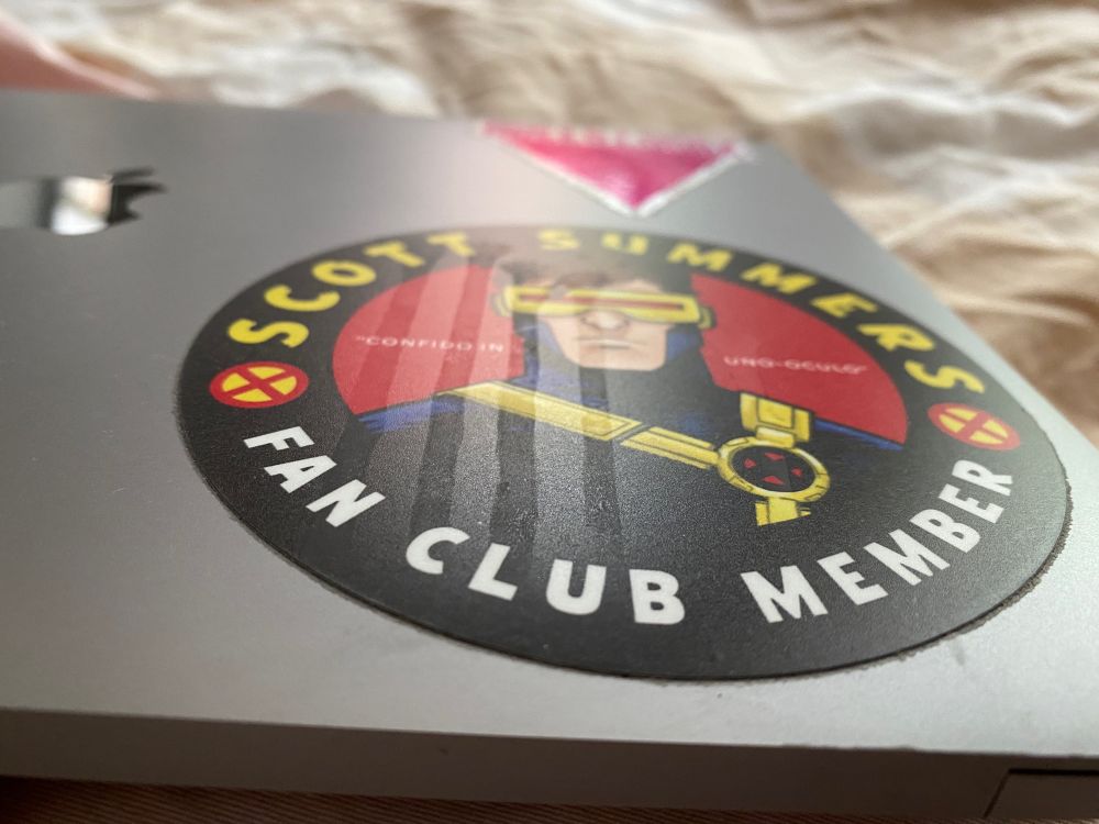 A laptop sticker for the Scott Summers Fan Club with four dried drip stains on it.
