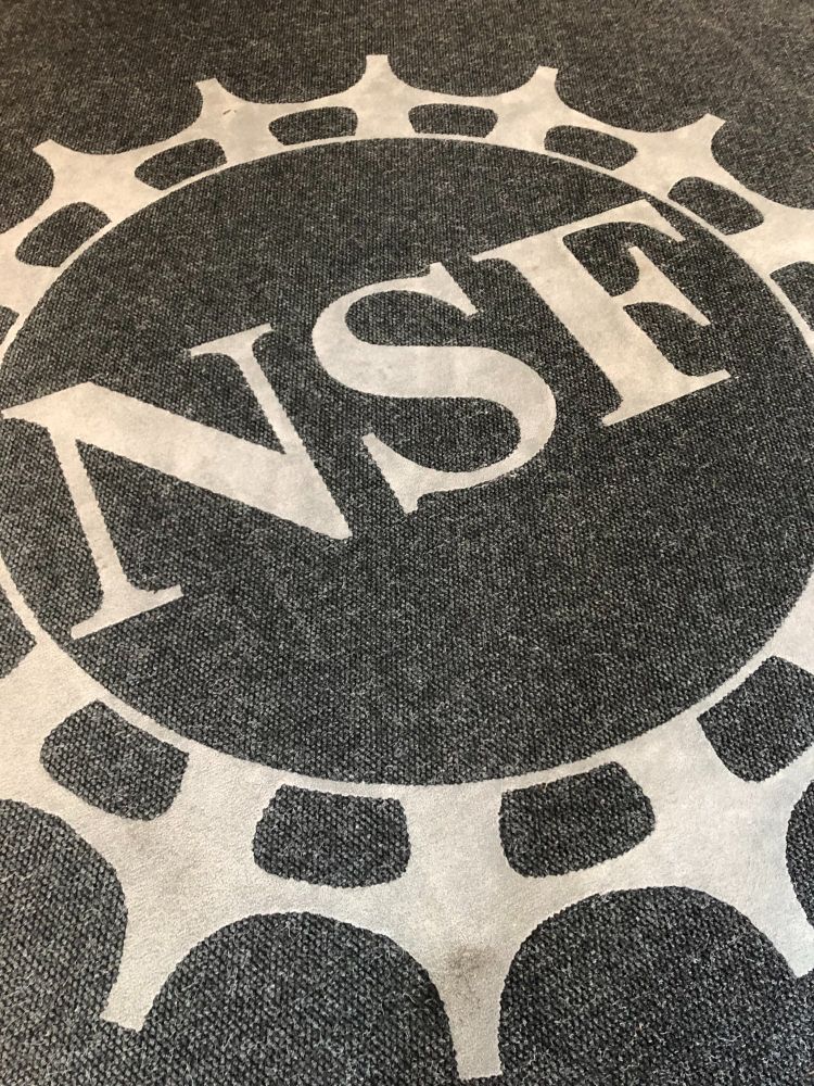 A photo of the NSF logo design on a carpet on the floor.