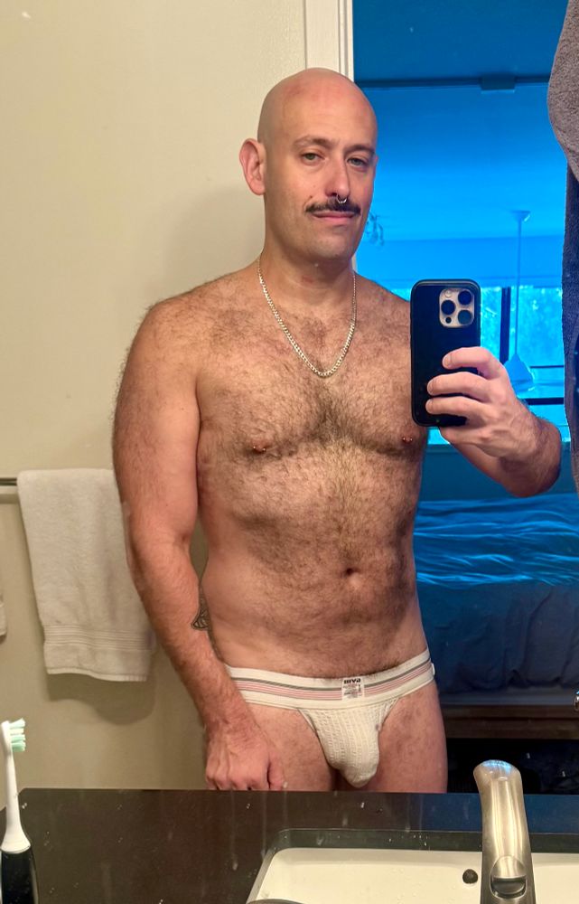 Hairy muscle otter daddy in a white jockstrap with visible penis line takes a mirror selfie 
