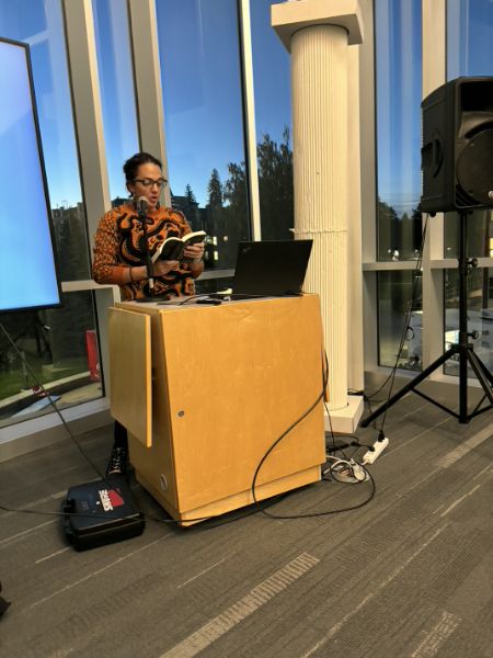 Picture of me reading at a podium with a sweater with a Minoan octopus design on it in black figure style