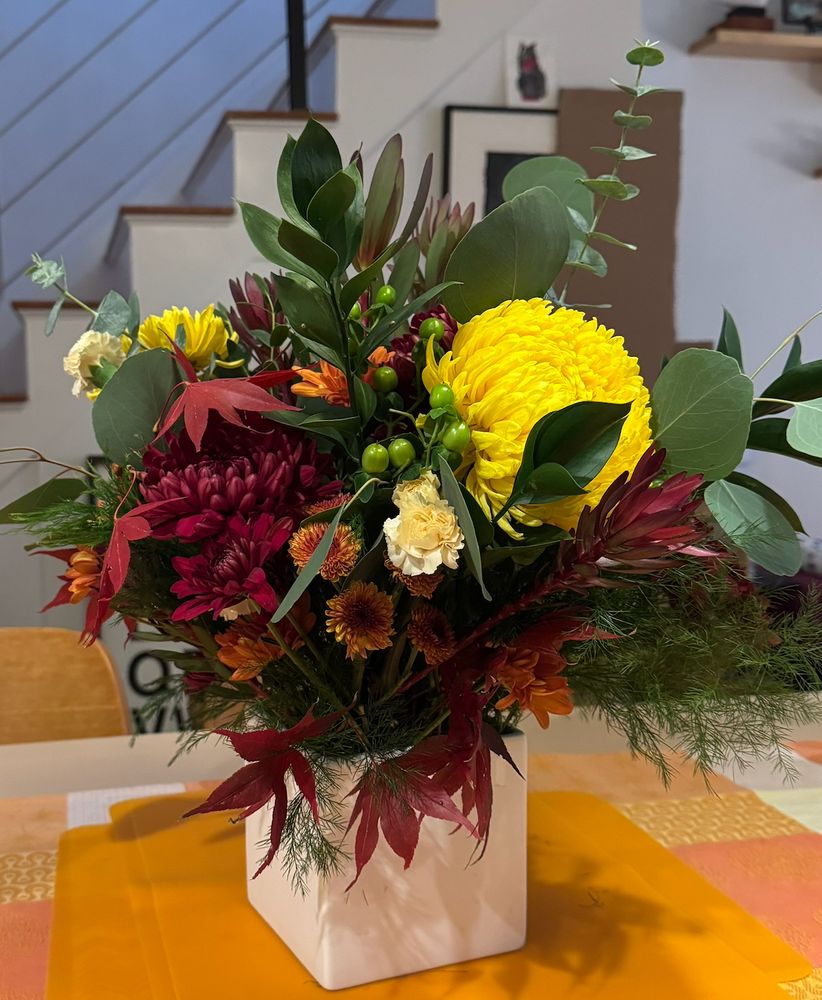 thanksgiving floral arrangement, yellows, oranges, reds, green foliage (5 different kinds of mums, two types of protea, greens, basically things that looked freshest at trader joe's)