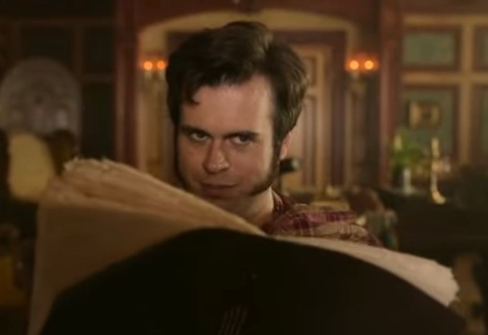 A photograph of Lucius Spriggs, looking coyly over his sketchbook. 