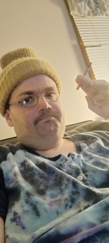 me in a beanie and tie dye shirt saluting with a cigarette