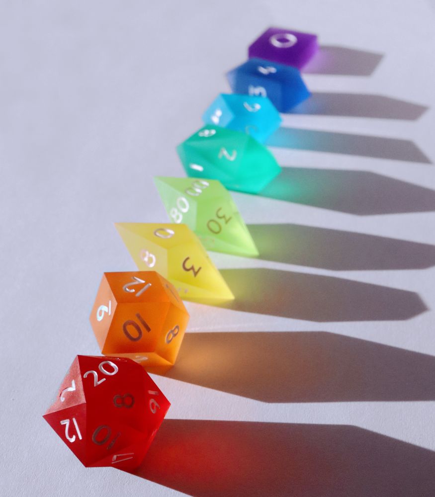 All 8 pieces of the dice lined up in raindow order starting with the red D20.