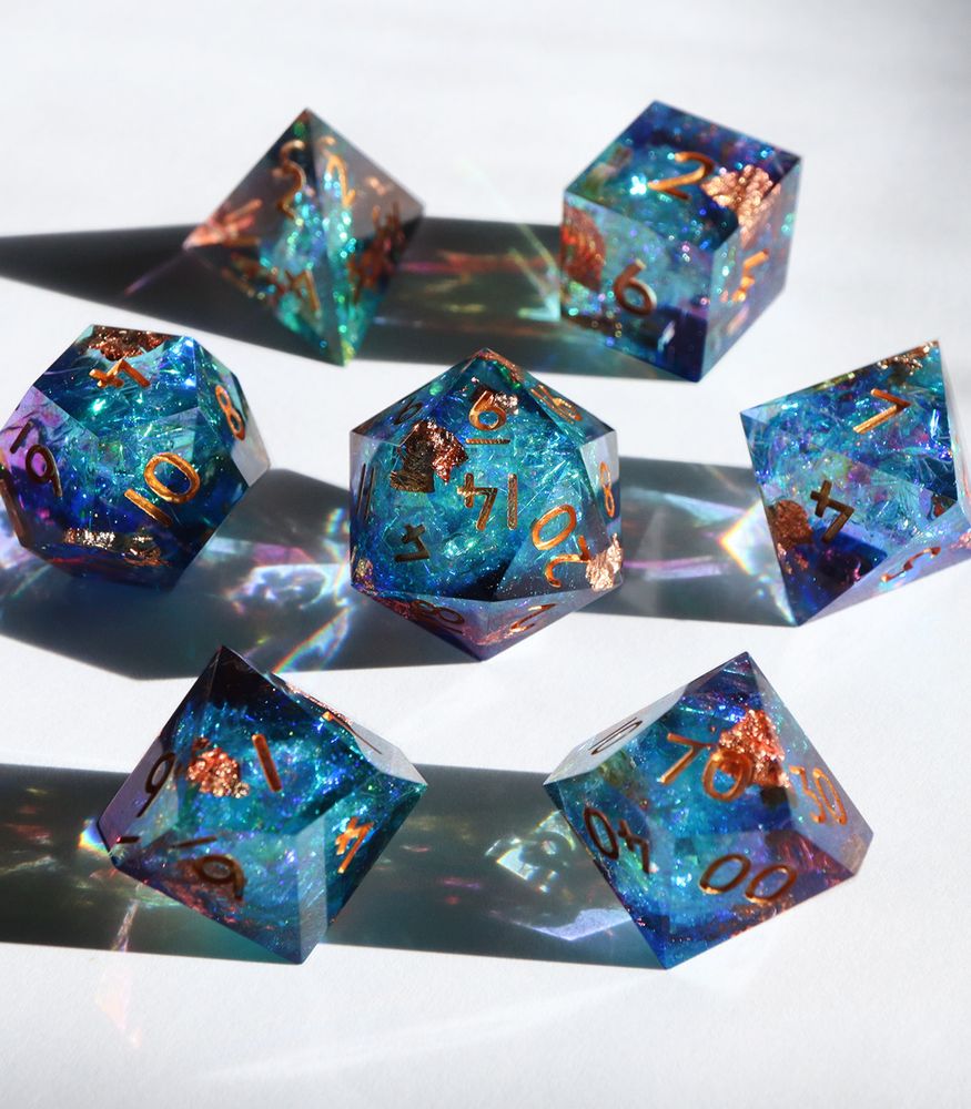 Full set of Nebula Patina arranged in a circle with the D20 in the center. All the dice are a mix of purple and blue resin with holographic foil inside that reflects colors of blue and green. There are copper foil flakes inside the side. The numbers on the dice are also copper.