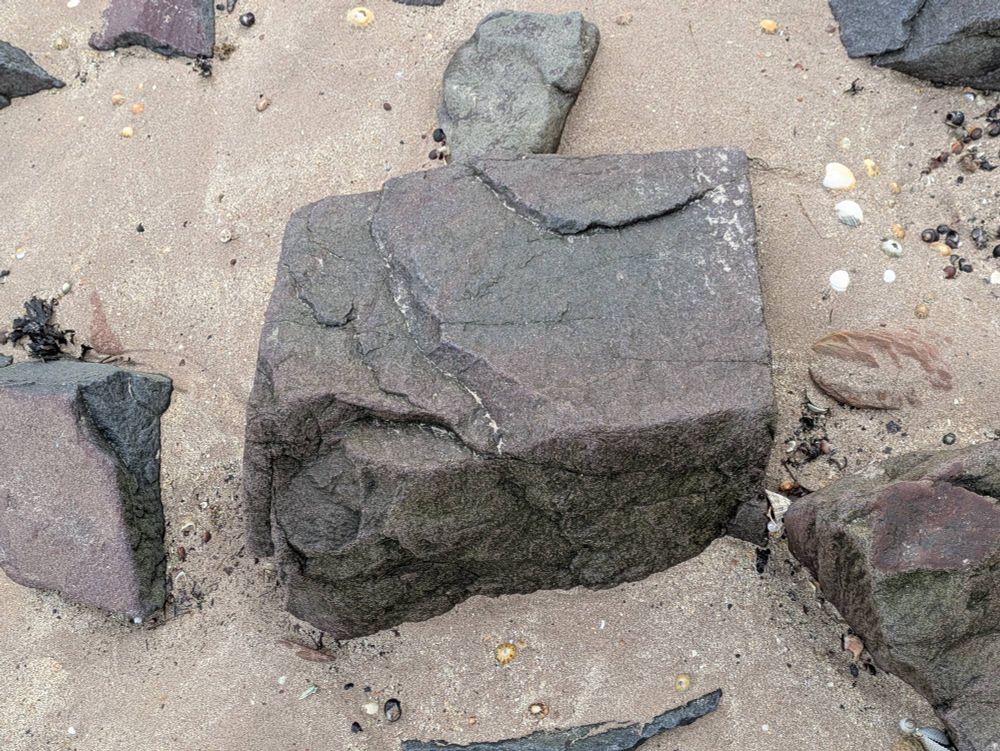 More lovely rocks sitting on sand. It's squareish and has lovely layering.