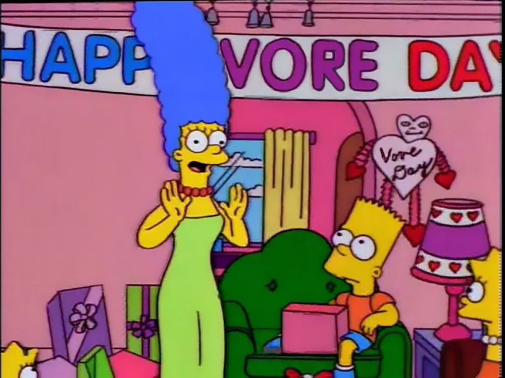 Marge Simpson standing in front of a banner that says "Happy Vore Day"