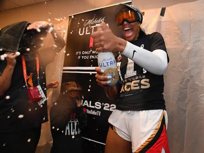 A’ja wilson celebrates her first title spraying a bottle of beer. She’s wearing her championship shirt and ski goggles