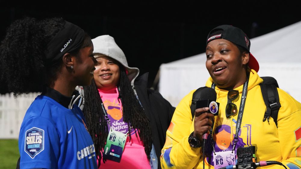 A closer photo from before, Eboni is speaking into the microphone, and Sylvs from sheabutter Fc is looking on