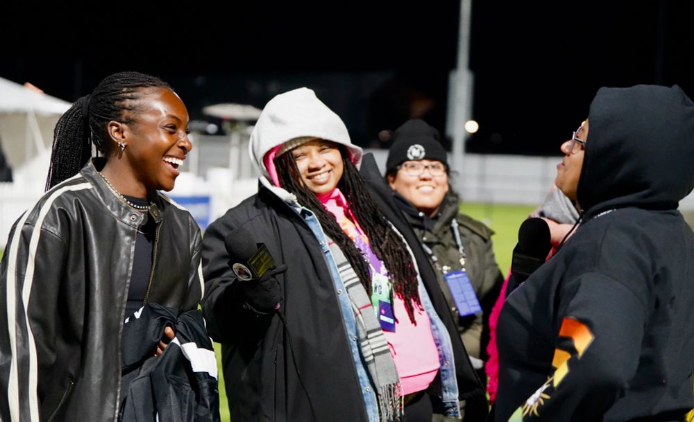 Skye is bundled up in the frigid KC weather, holding a microphone out for Michelle Alozie, and smiling