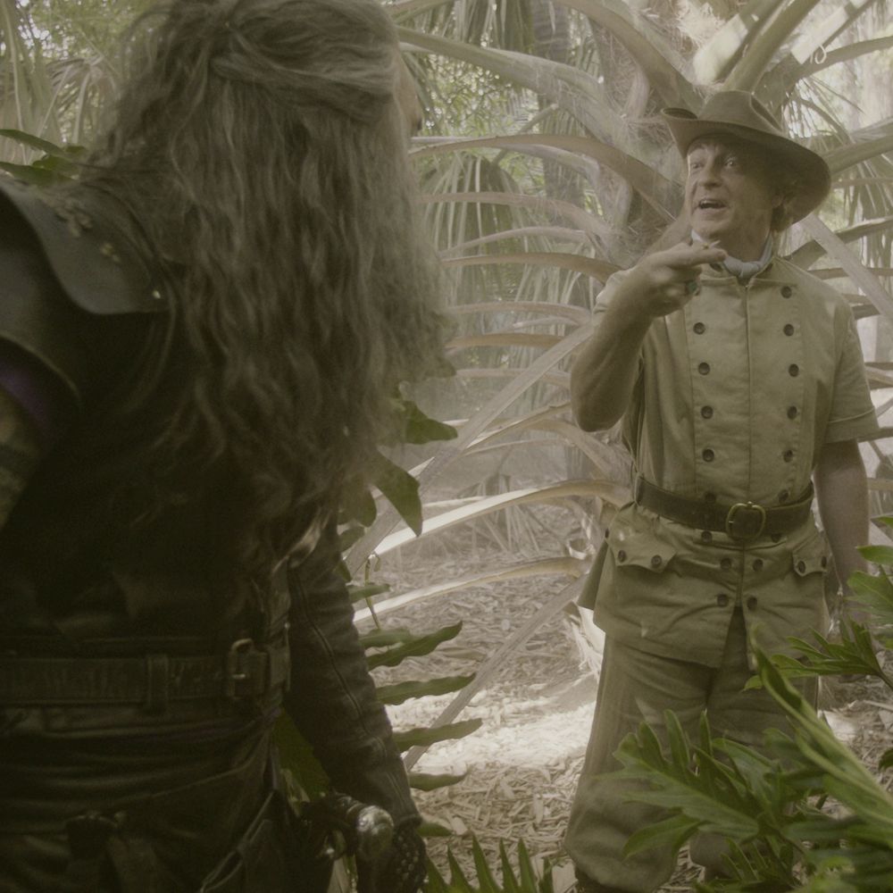 screenshot from ofmd 1x7; stede is wearing his beige adventurer outfit and its hat; he is showing ed the rosy maple moth, arm extended, and ed (back to camera) is unimpressed