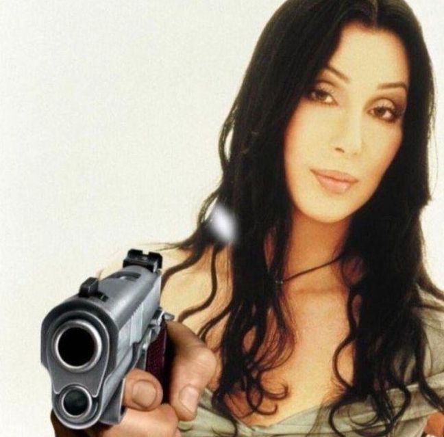 Cher pointing a gun at the viewer 