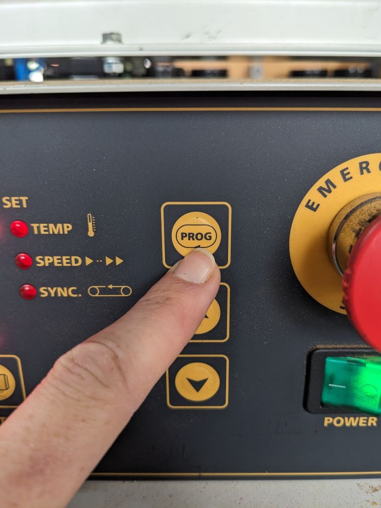 a finger pointing to a button on a control panel labelled "prog"