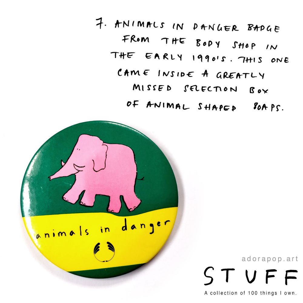 A photograph from adorapop.art's "Stuff" series. It's a 2 inch badge from The Body Shop that reads "animals in danger" and shows a pink elephant on a green background. This was part of a campaign to raise awareness about endangered species run by The Body Shop in the early 1990's.

Handwritten text reads: 7. Animals in Danger badge from The Body Shop in the early 1990's. This one came inside a greatly missed selection box of animal shaped soaps.