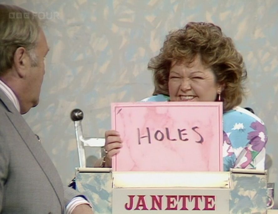 Jeanette Krankie holding up a card that says "HOLES"