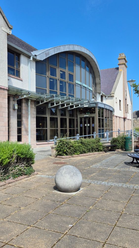 An image of Orkney library with blue sky overhead and a shiny concrete ball in front