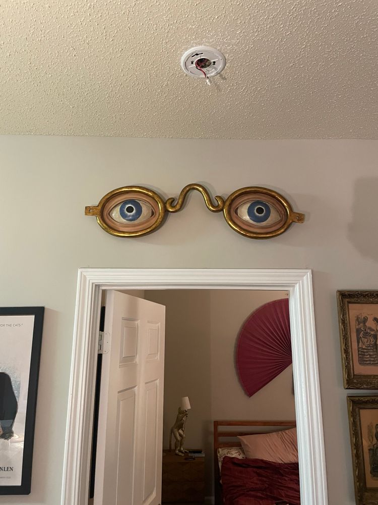 What’s officially called the “Optomotrist Sculpture,” it’s a pair of bespectacled eyes in gold frames hung up above our bedroom door frame. 