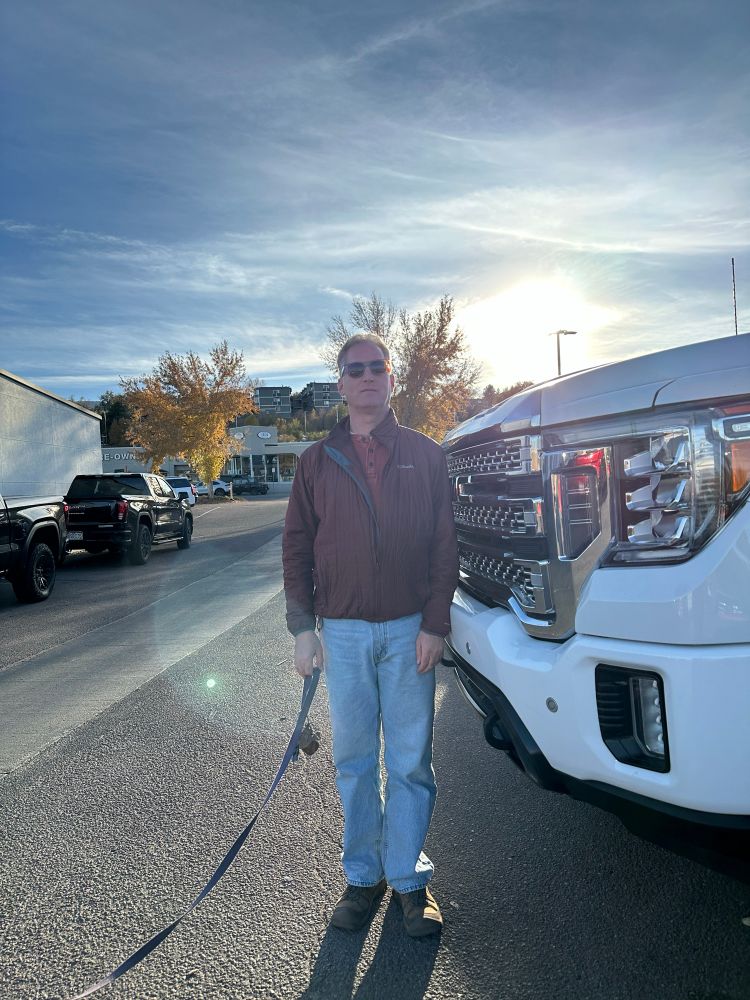 An adult man, 6’1” tall, stands in front of a giant pickup truck. His shoulders don’t even clear the top of the hood.