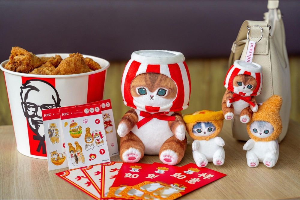 An image of the products available in the KFC x Mofusand collaboration, which includes a series of plushy cats with chicken pot pie, drumstick, and KFC buckets as hats.