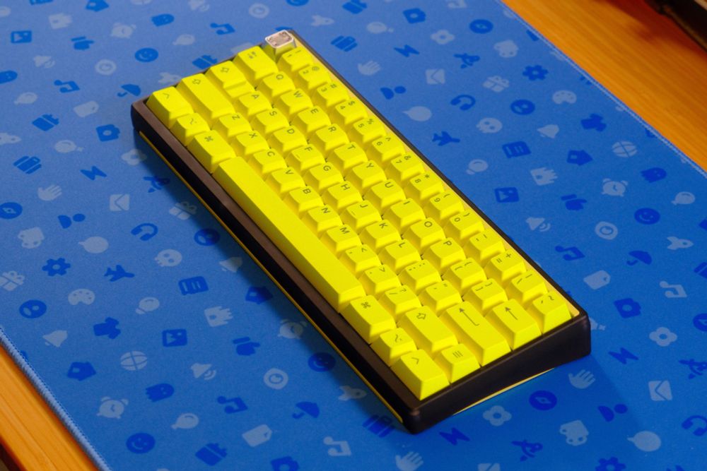 Luminkey60 LX (bright neon and dark polycarbonate keyboard) with GMK Hi! Viz keycaps on a blue Font Awesome deskpad