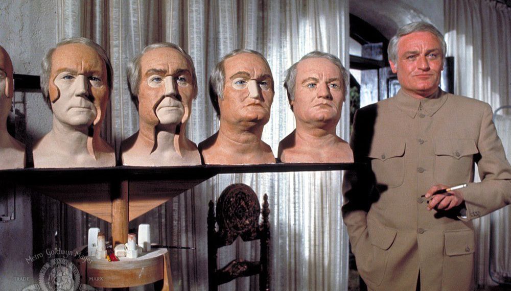 Blofed in DAF stood next to a row of his fake heads, each more complete than the last
