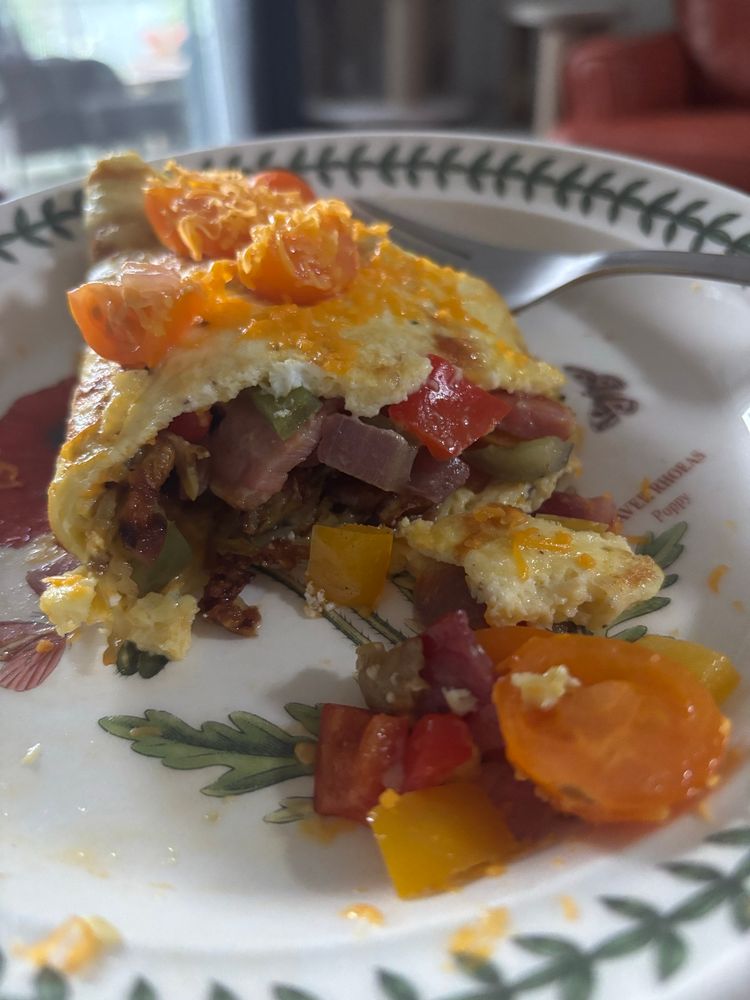 Partially eaten omelette with the insides spilling out onto the white plate 