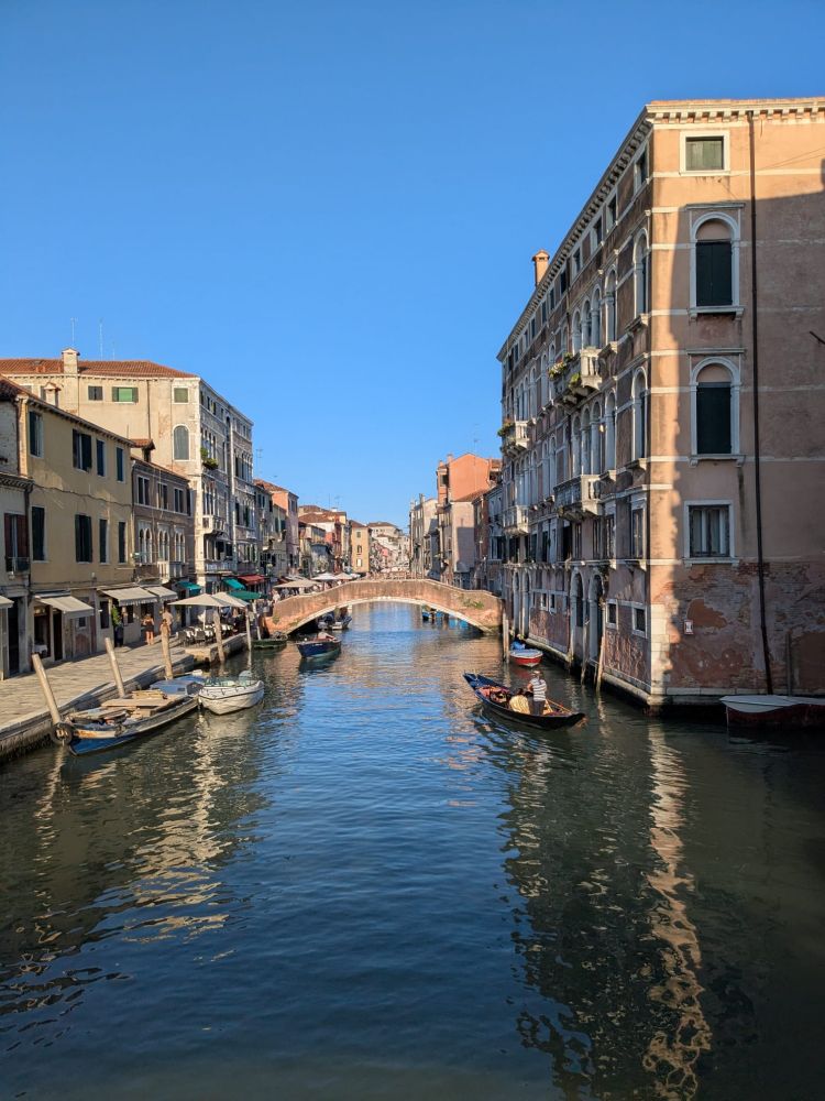 A gondola works it's way up a Venice canal under an azure blue sky.
