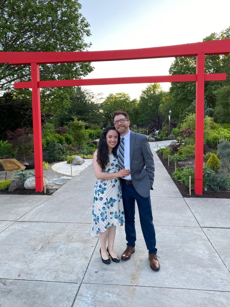 Mary and me, dressed up, red archway behind us, leading to gardens.