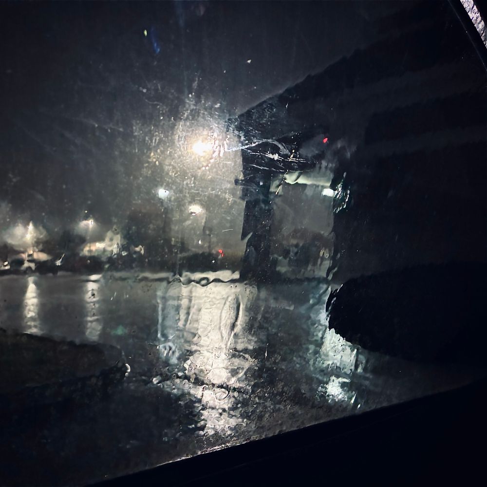 A rainy parking lot as taken through a car window 