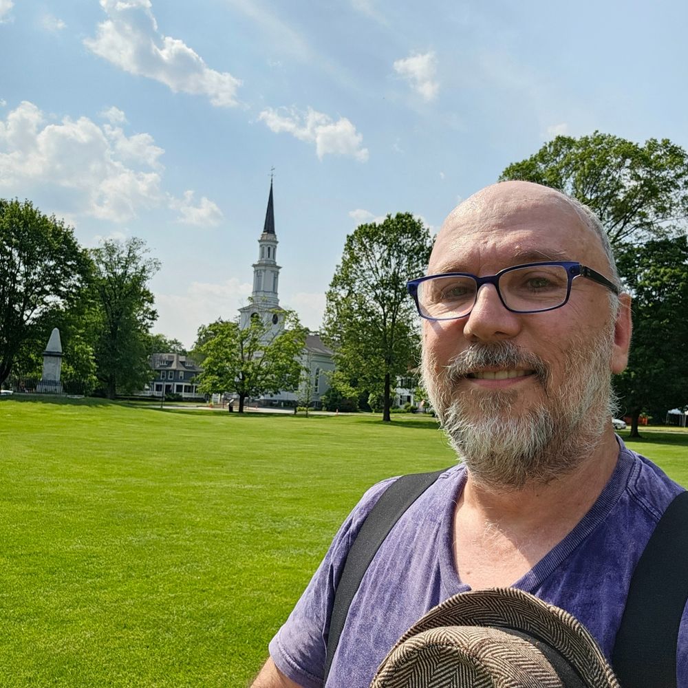 Some old guy stands on a lawn with a church in the background. Some kind of history and stuff.
