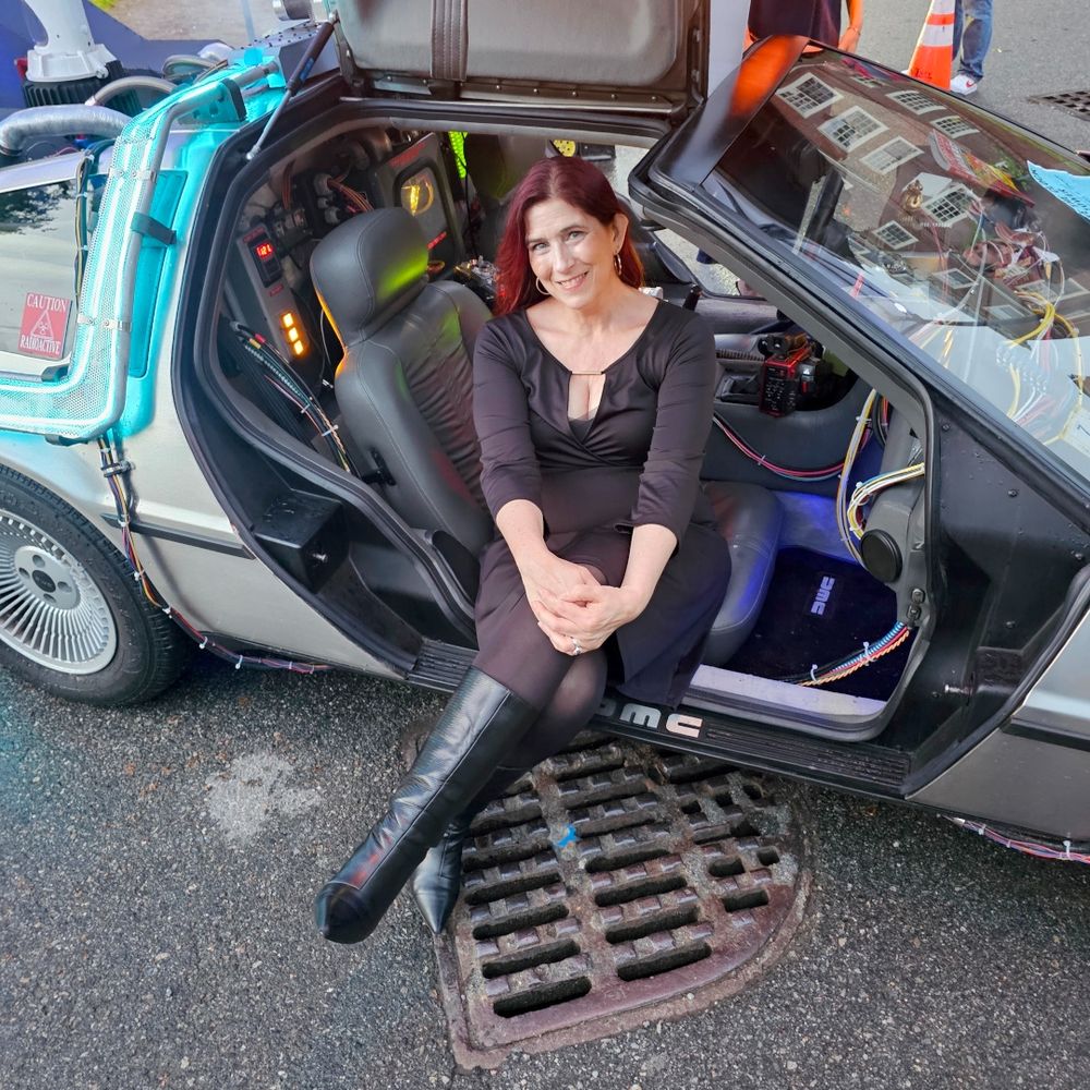 Demeter sitting in the passenger seat of the BttF Delorean.