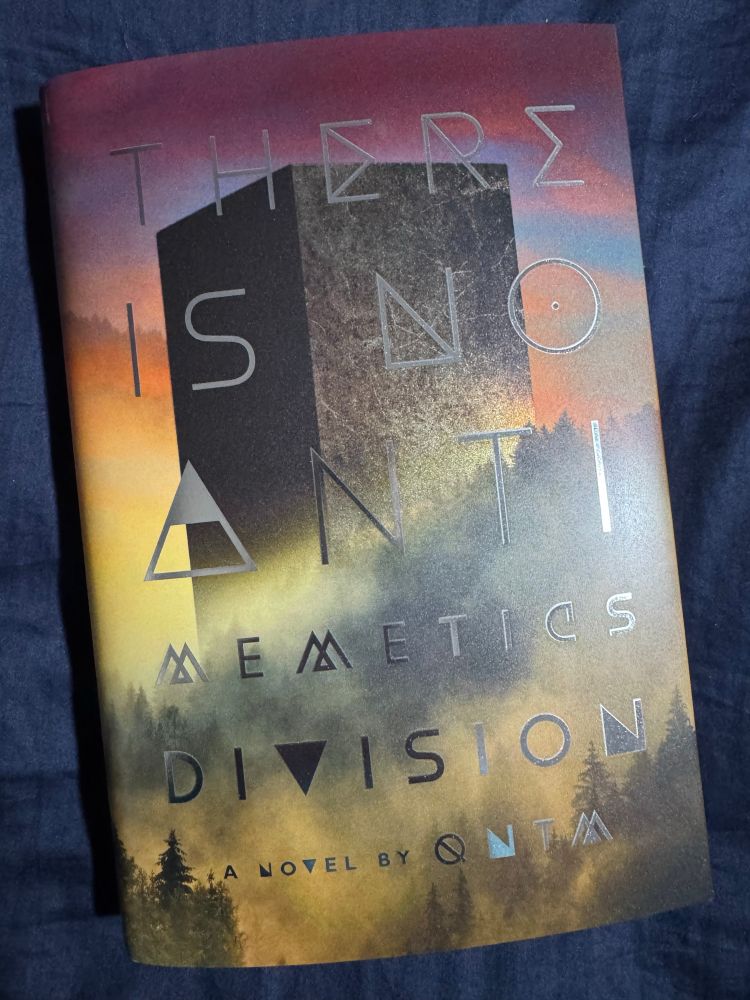 Book cover of There Is No Antimemetics Division shows an enormous black tower with no visible windows. The sky is orange and gold. The building towers above trees and low lying fog. 