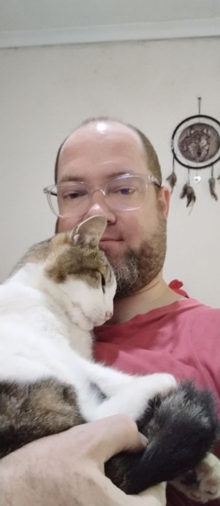 A man holding a cat in his arms, cat is content on being held