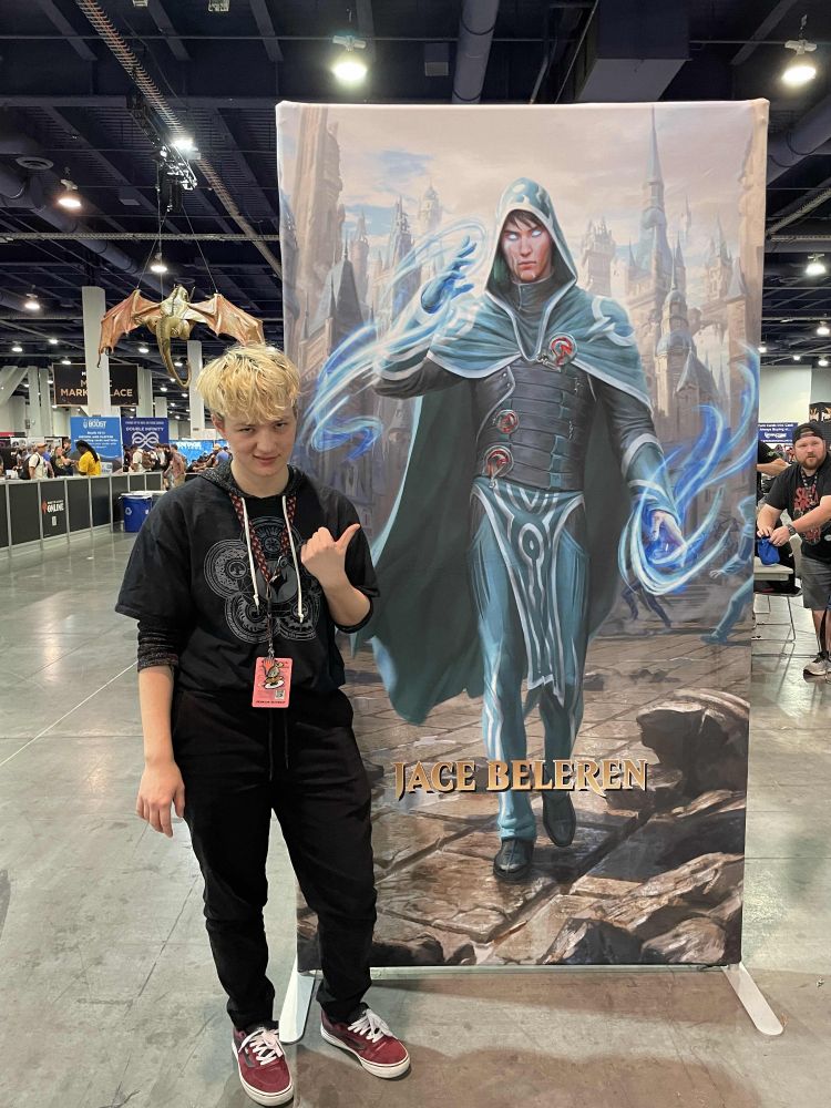 A picture of me standing next to a 7ft tall Jace poster. I am pointing at him and I look disgusted/unamused.
