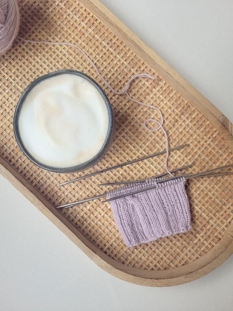 ENG A knitting project - lilac socks, the ribbing is just finished - and a cappuccino in a small handmade cup

DEU Ein gerade begonnenes Strickprojekt, eine Socke aus Wolle in hellem Lila, und ein Cappuccino in einem kleinen, handgetöpferten Becher 