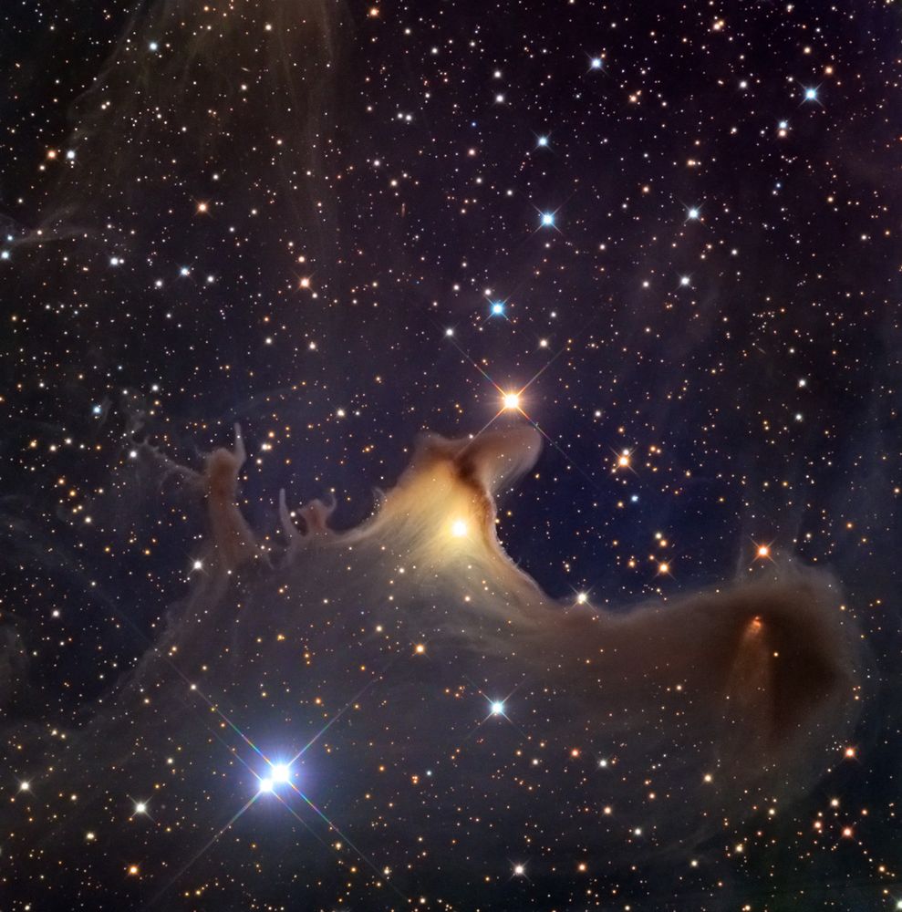 A dusty white and brown nebula illuminated from within by a bright yellow star. It looks like a sheet ghost with its arms spread wide, against a dark purple-blue-black background covered in glittering stars.