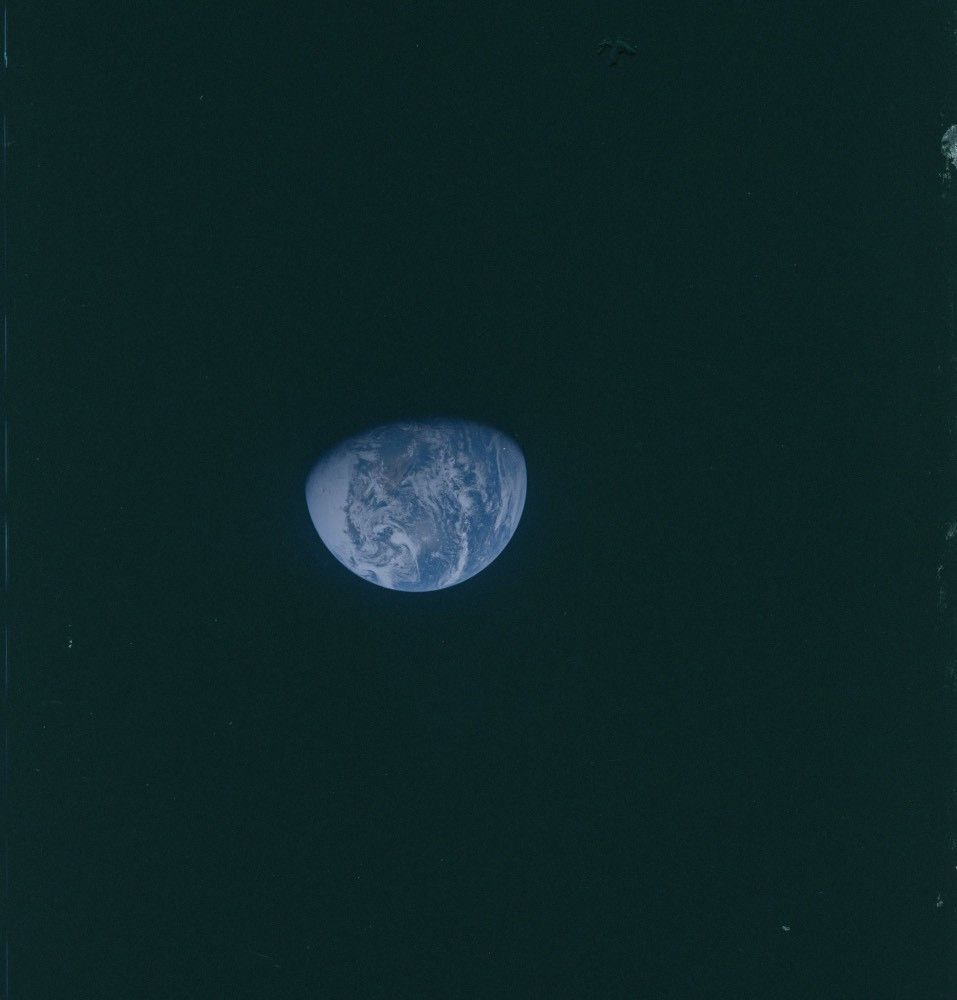 The blue Earth hanging in space, with about a third of its disk covered in shadow. Land masses and clouds are visible, but the blue of ocean is most prominent.