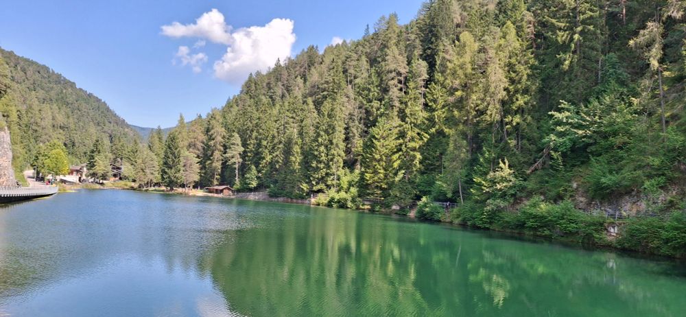 Emerald colored lake named lake Emerald, you can see pine woods reflecting on the water, it's sunny