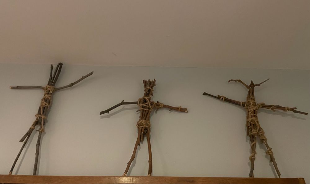 Three human-shaped figures made of twigs