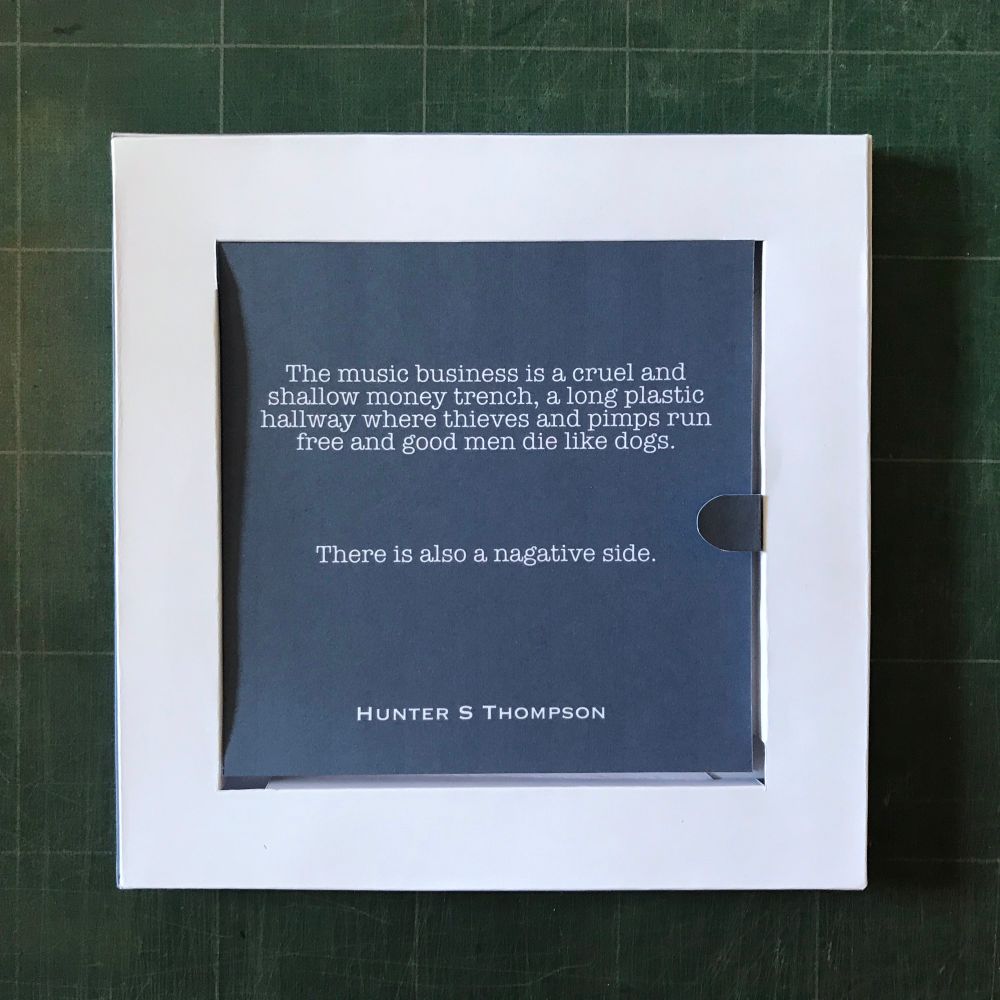 Lid removed revealing the first card. It says “The music business is a cruel and shallow money trench, along plastic hallway where thieves and pimps run free and good men die like dogs. There is also a negative side. Hunter S Thompson”